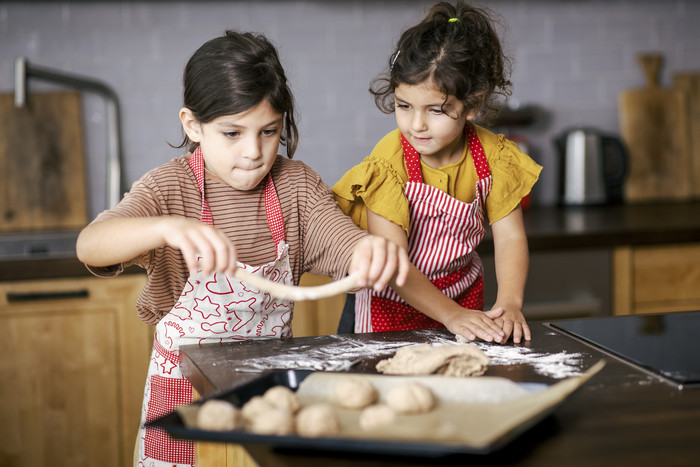 Foto: Sarah Wiener Stiftung | photothek Zwei Kinder legen Teig in verschiedenen Formen auf ein Backblech
