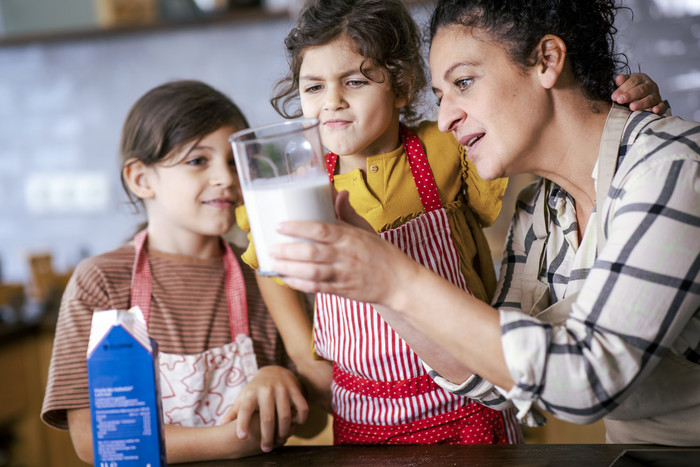 Foto: Sarah Wiener Stiftung | photothek Eine Frau zeigt zwei Kindern ein Glas Milch