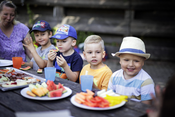Sarah Wiener Stiftung | photothek Vier Kinder und eine Erwachsene an einem Tisch mit Rohkosttellern